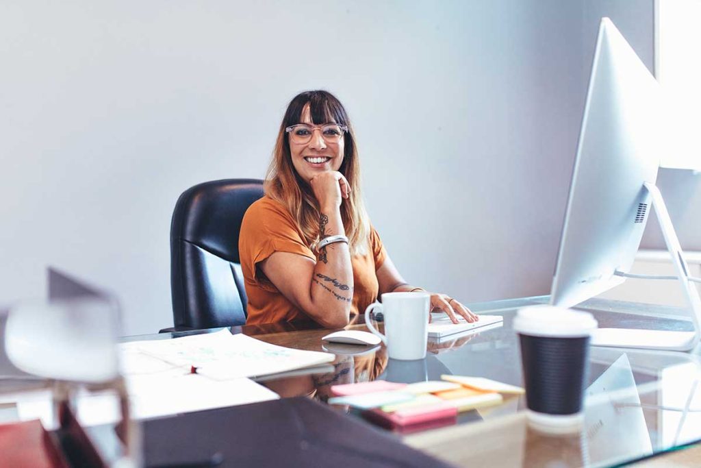 Leende kvinna vid sitt skrivbord